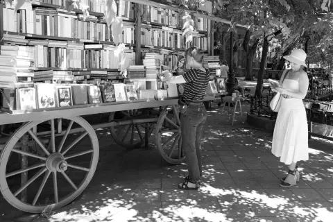 Deux passantes choisissant des livres a un etal ambulant ombrage, Budapest