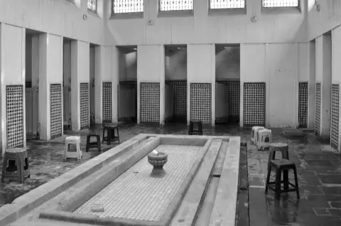 Bassin carrele et tabourets alignes dans un hammam desert, Casablanca