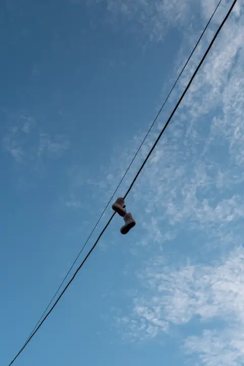 A pair of shoes hanging from a cable against the blue sky, Christiania, Copenhagen