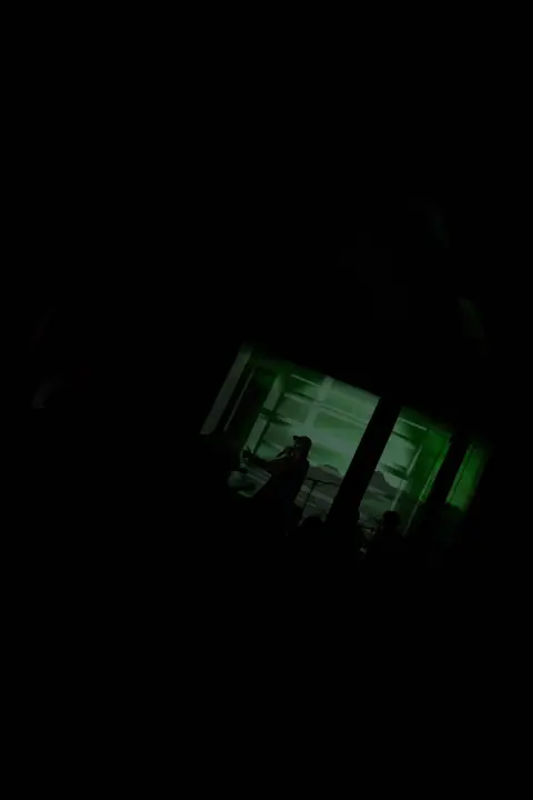 A silhouette behind a green-lit window in the dark, Christiania, Copenhagen