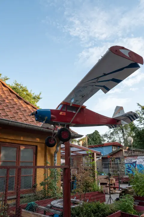 A small red and white plane perched above a house, Christiania, Copenhagen