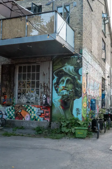 A face painted in green and blue on the facade of a brick building, Christiania, Copenhagen