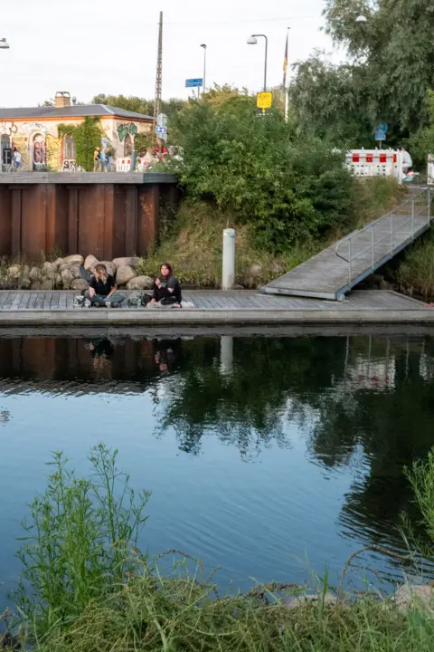Two people sitting on a pontoon by the canal, Copenhagen