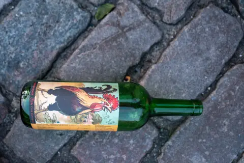 An empty bottle with a rooster label lying on the cobbles, Copenhagen