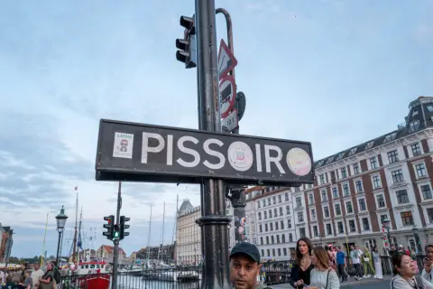 A “Pissoir” sign above the evening crowd, Nyhavn, Copenhagen