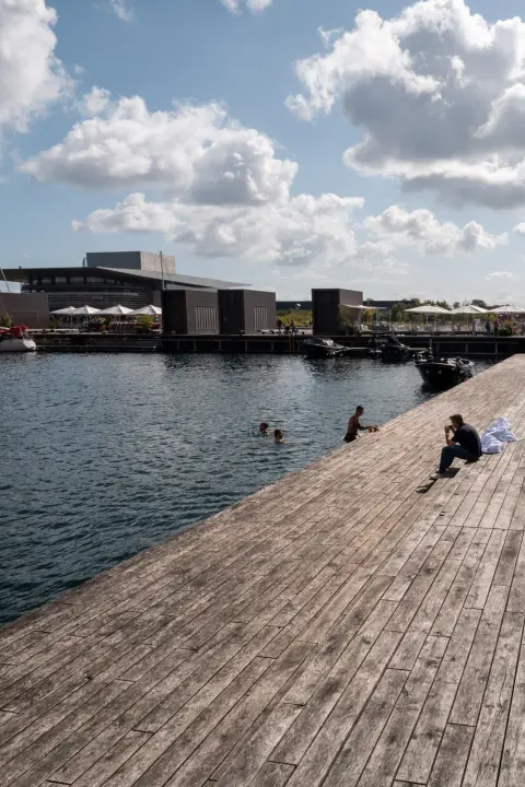 A wooden deck at the edge of the harbour, swimmers in the water, Copenhagen