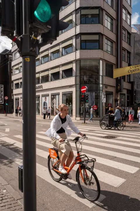 A cyclist on an orange bike crossing at the crosswalk, Copenhagen