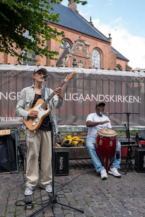 Two musicians, guitar and conga, in front of the Church of the Holy Spirit, Copenhagen