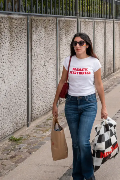 A woman in a “Dramatic overthinker” T-shirt, her arms full of bags, Copenhagen