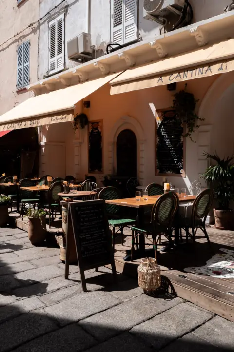 Terrasse vide d’un restaurant sous ses stores, dans une ruelle ensoleillée, Calvi, Corse