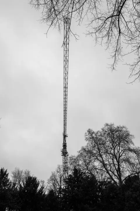 Pylone metallique elance depassant des branches d'arbres denudes, Düsseldorf