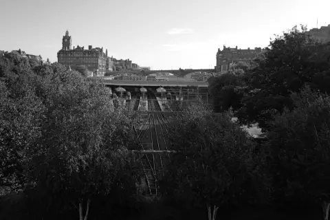 Waverley station tracks between the trees, a clock tower in the distance, Edinburgh