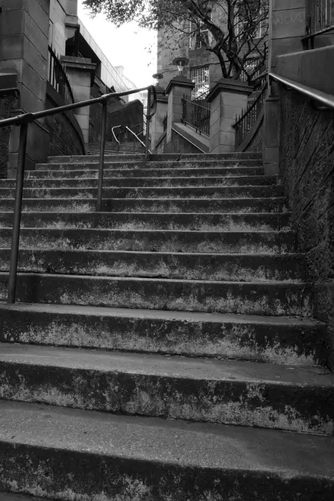 Worn stone stairway between two walls, metal handrails, Edinburgh