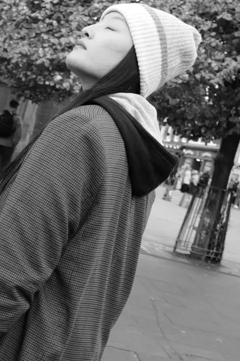 Young woman in a beanie, eyes closed, face turned to the sun, Edinburgh