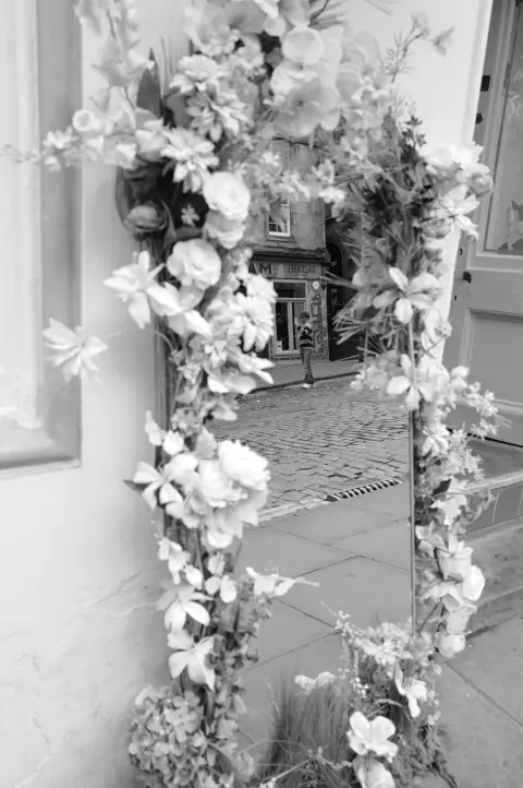 Mirror framed with artificial flowers reflecting a cobbled street, Edinburgh