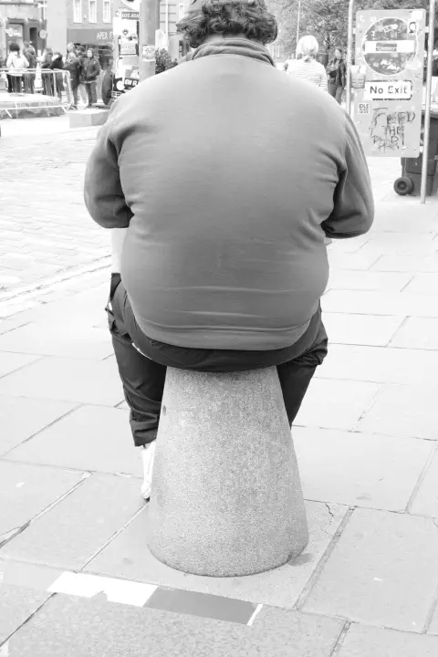 Man seen from behind sitting on a stone bollard, Edinburgh