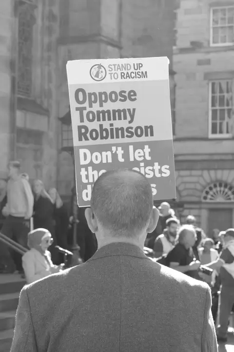 Man seen from behind facing an anti-racism placard at a rally, Edinburgh