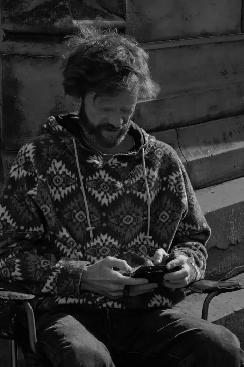 Bearded man in a patterned hoodie absorbed in his phone, Edinburgh