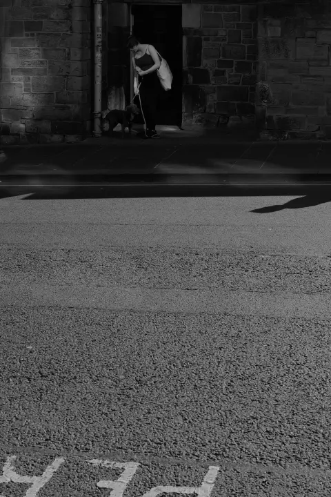 Figure in a doorway above a sunlit street, Edinburgh
