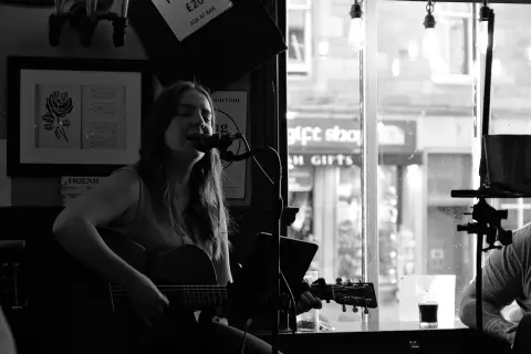 Singer with a guitar performing in a pub, Edinburgh