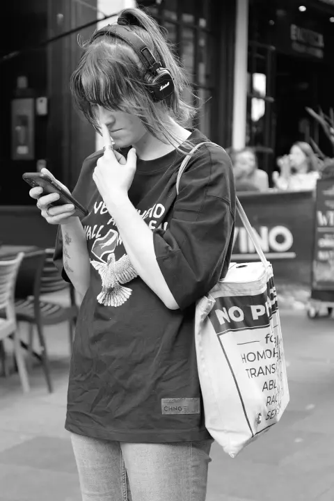 Young woman with headphones, puzzled by her phone, Edinburgh