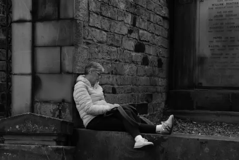 Woman resting at the foot of a graveyard wall, Edinburgh