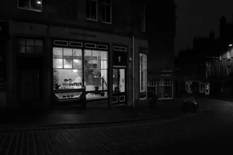 Lit shop window on a cobbled corner at night, Edinburgh
