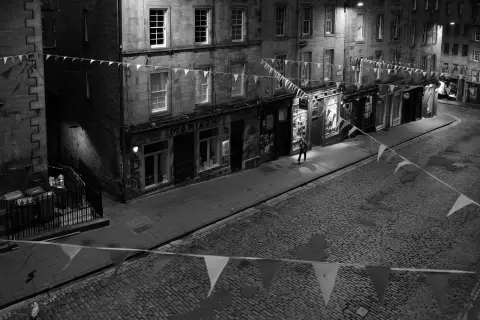 Curving cobbled street seen from above, bunting strung across, Edinburgh