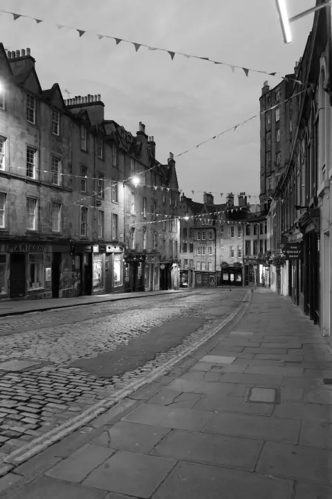 Sloping cobbled street lined with old facades and bunting, Edinburgh