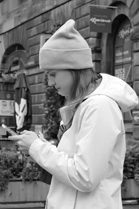 Young woman in a beanie checking her phone, Edinburgh
