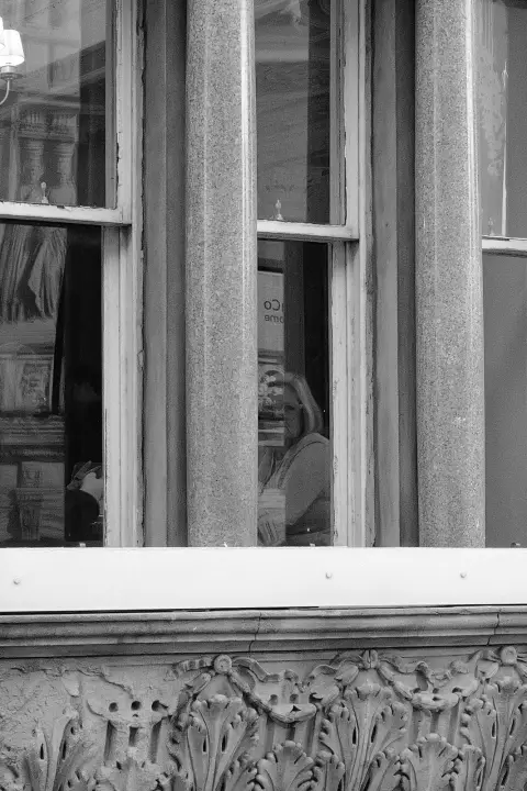 Woman glimpsed through a café window between columns, Edinburgh