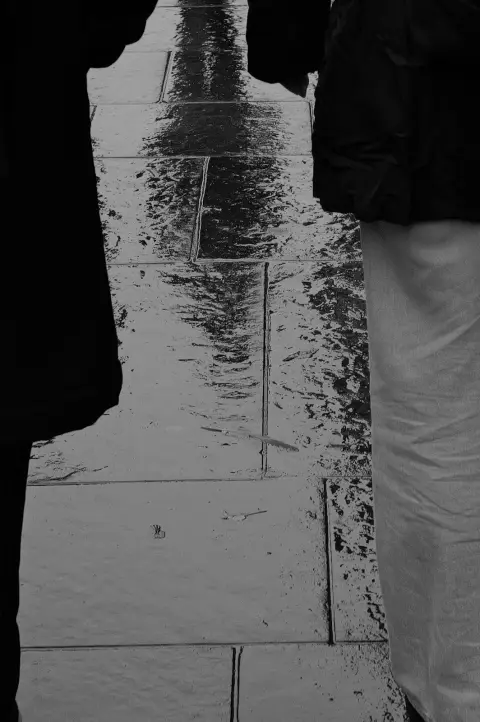 Reflections on a wet pavement between two figures, Edinburgh