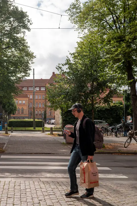 A man in headphones crossing the street with a shopping bag, Gothenburg