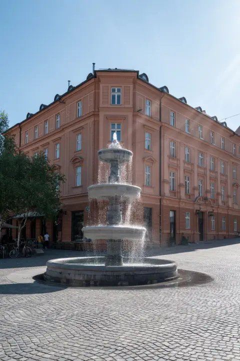 Fontaine a etages jaillissant devant un immeuble rose, Ljubljana