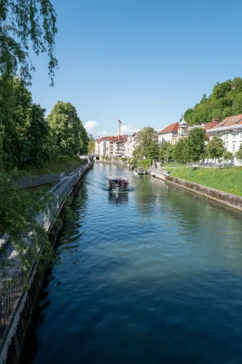 Bateau de croisiere glissant sur la riviere vers la colline boisee, Ljubljana