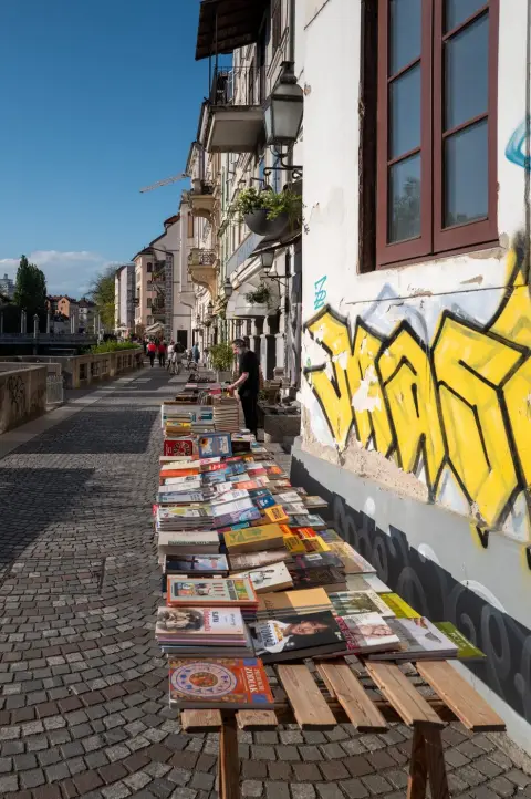 Etals de livres d'occasion pres d'un mur graffe, Ljubljana