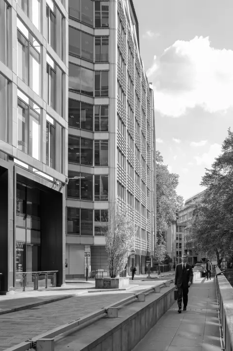 Homme d'affaires en costume marchant seul entre les tours de bureaux vitrées, Londres