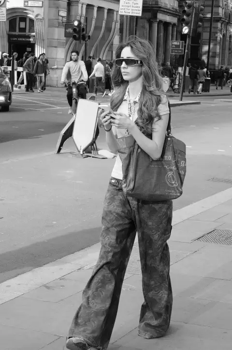 Jeune femme en lunettes de soleil traversant la rue en consultant son téléphone, Londres