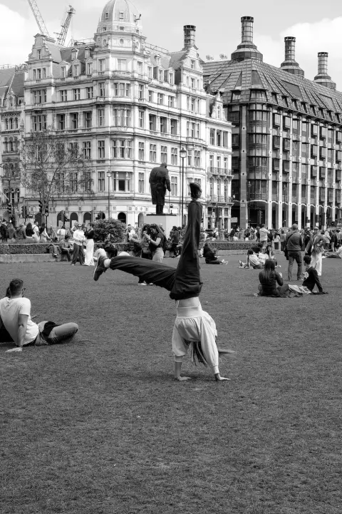 Un artiste de rue en équilibre sur les mains devant les immeubles de Parliament Square, Londres