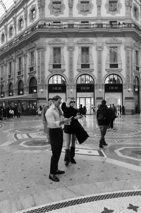 Couple élégant consultant son téléphone devant les vitrines Dior de la Galleria, Milan