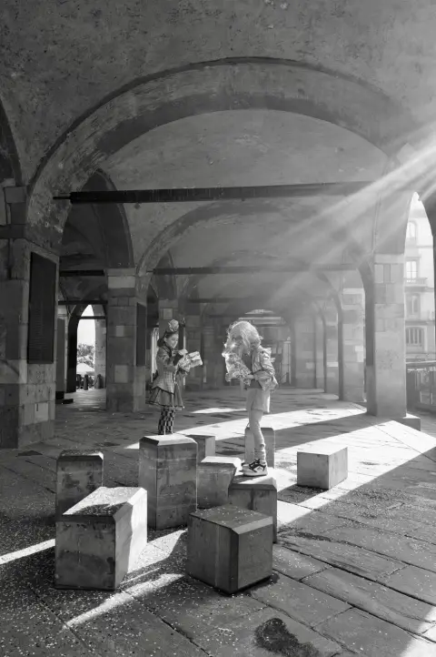 Deux enfants perchés sur des blocs de pierre, rayons de lumière traversant une arcade, Milan