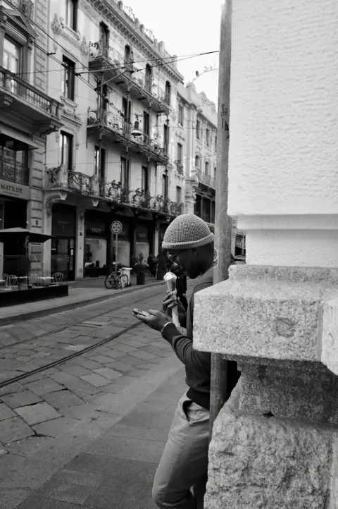 Homme en bonnet dégustant une glace tout en consultant son téléphone, Milan