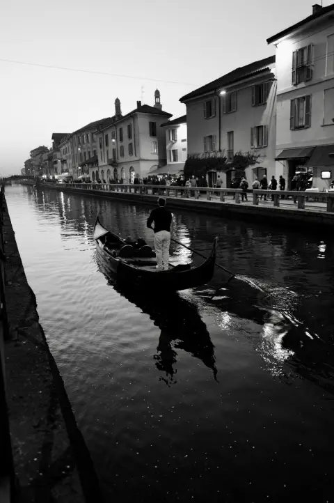 Gondolier debout guidant sa barque sur le Naviglio à la tombée du jour, Milan