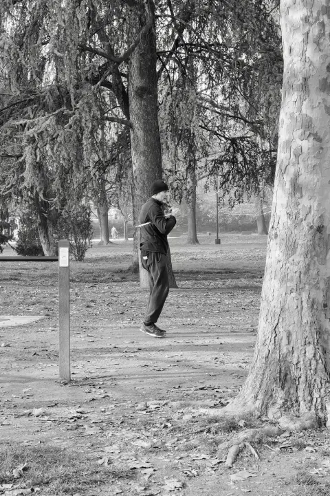 Un homme en bonnet pratique le tai-chi avec une épée sous les arbres, Milan