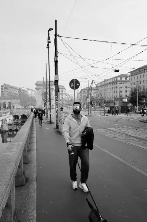 Homme barbu aux lunettes miroir promenant son chien le long du canal, Milan