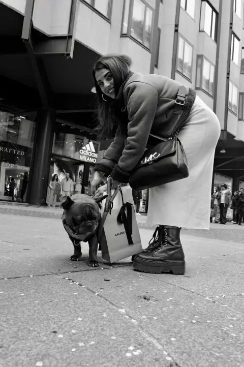Jeune femme penchée vers son bouledogue français, sac Balenciaga à la main, Milan
