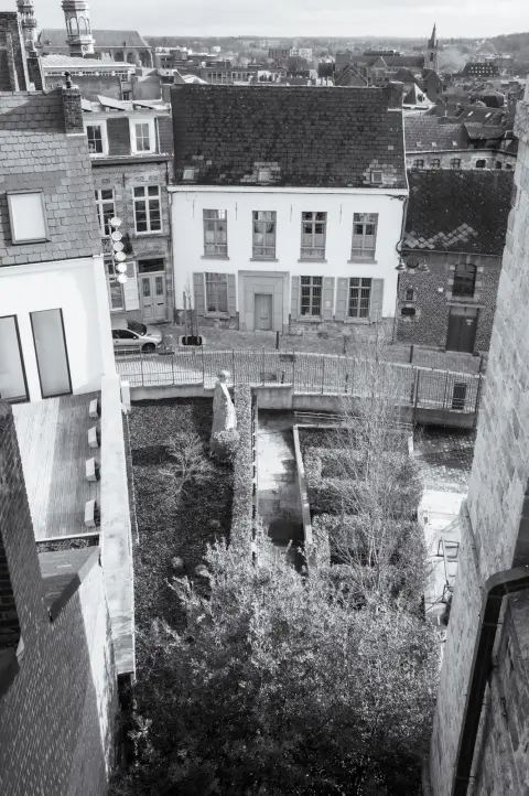 Vue plongeante sur des jardins et des toits entre deux façades, Mons