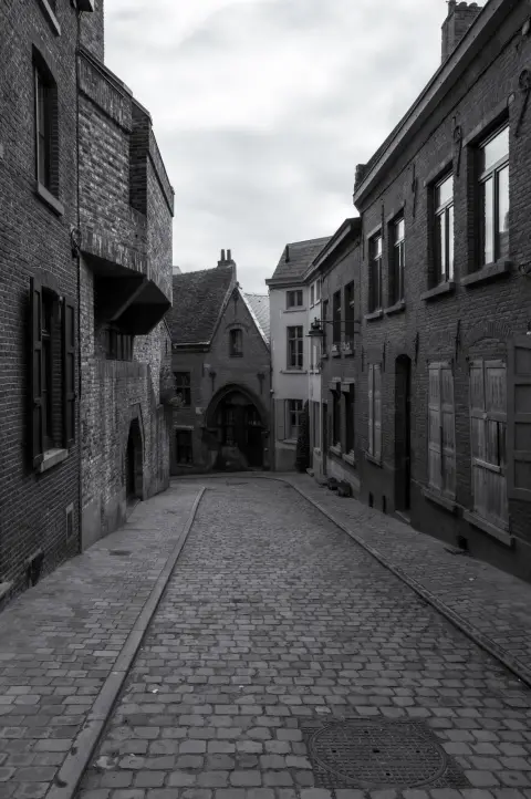 Une ruelle pavée déserte entre des maisons de briques, Mons