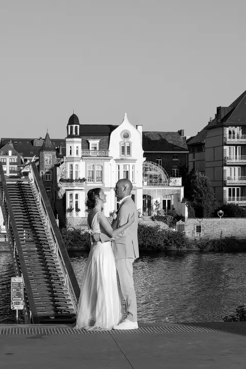 Mariés s’enlaçant sur une passerelle, façades Belle Époque en arrière-plan, Namur