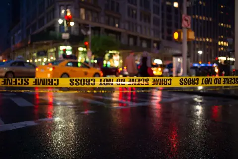 Ruban de scène de crime en premier plan devant une avenue animée la nuit, New York